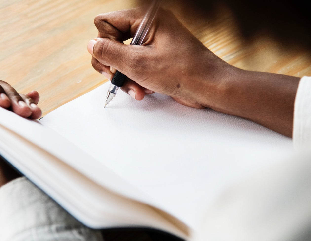 A Black woman journaling by hand